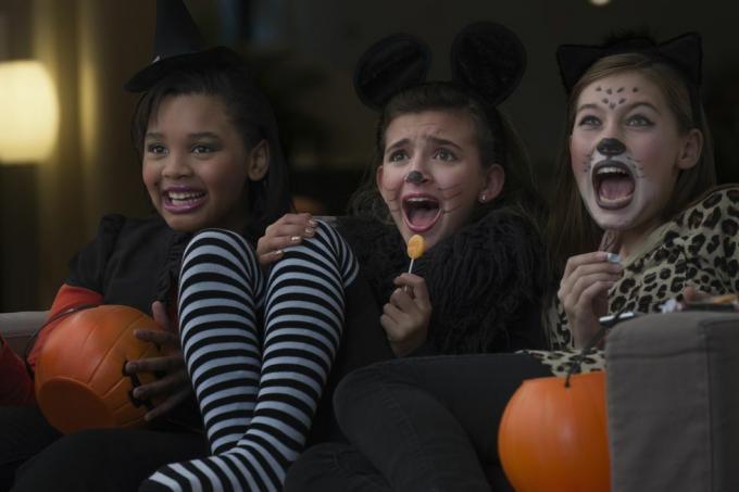 वेशभूषा में लड़कियाँ हेलोवीन पर एक साथ डरावनी फिल्म देख रही हैं